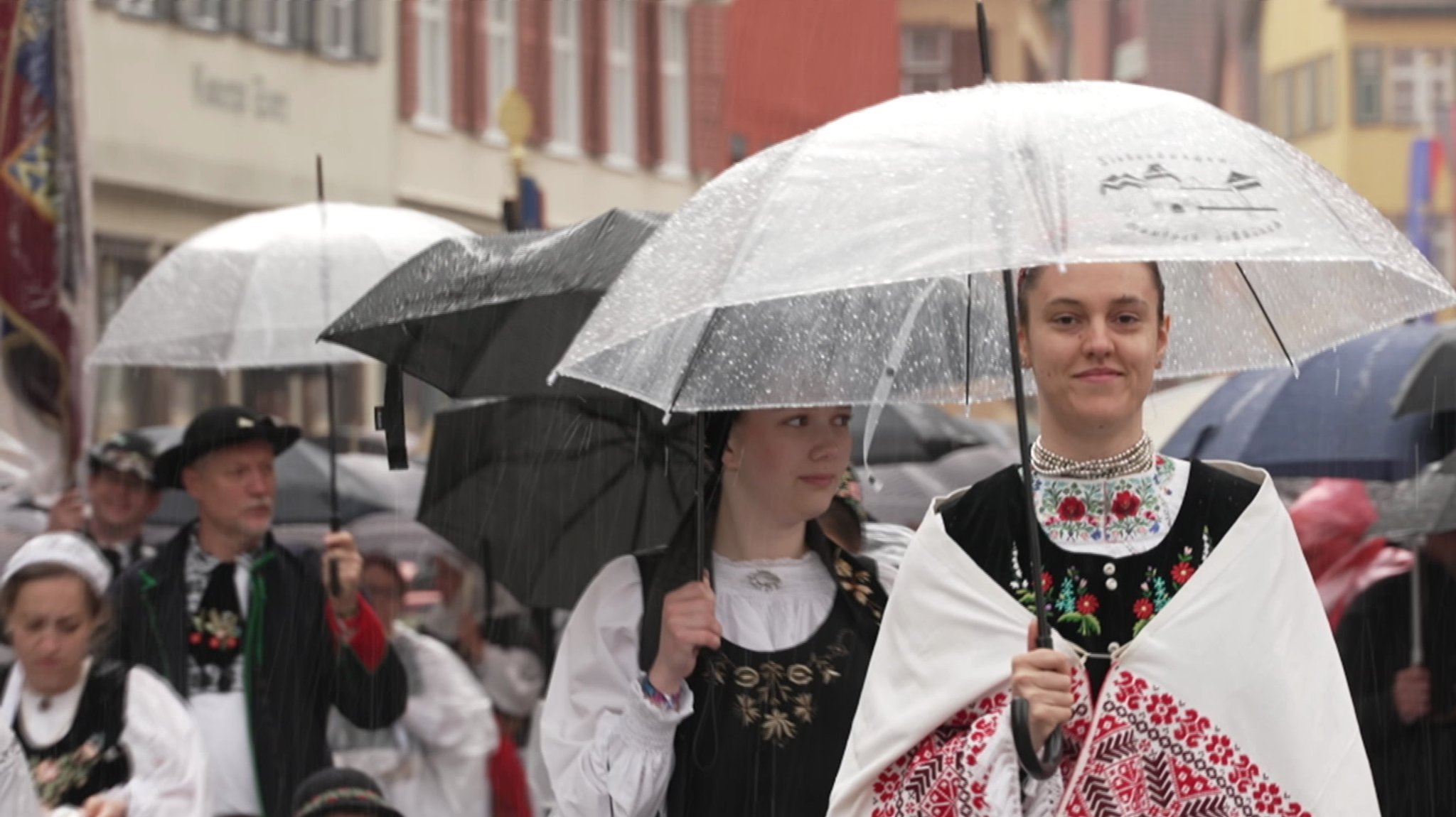 Menschen tragen Tracht und Regenschirme
