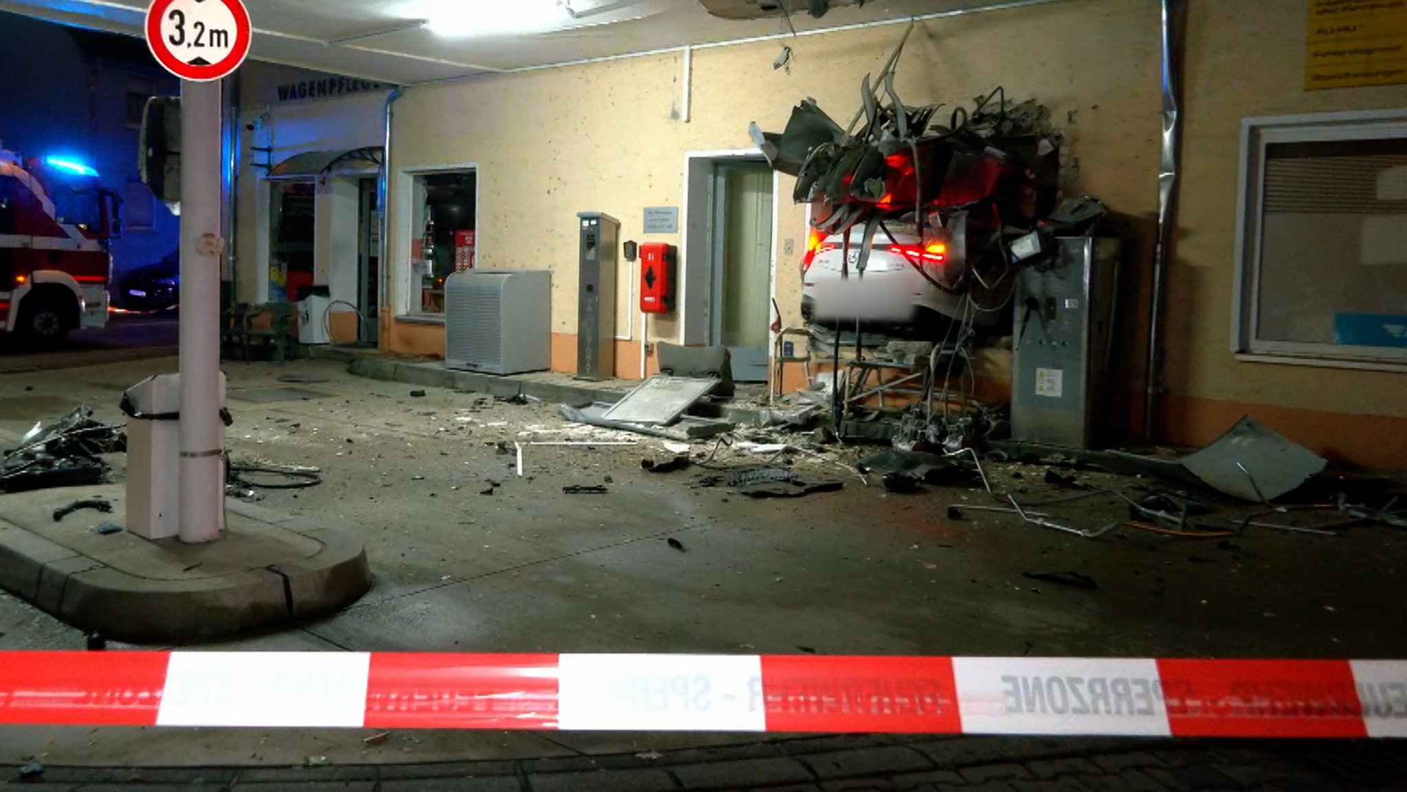 Die zerstörte Tanksstelle mit Absperrband und Auto in der Wand